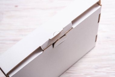 Tahta masadaki beyaz karton kutu, düz uzan. 