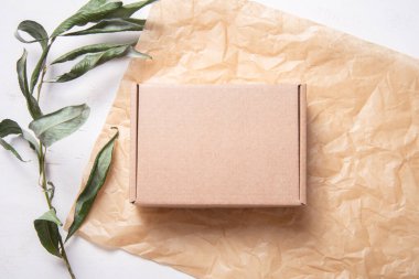 Taze yeşil yapraklar üzerinde kahverengi karton kutu