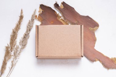 Kurumuş yapraklarla süslenmiş kahverengi düz karton kutu.