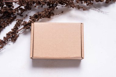 Kurumuş dallarla süslenmiş kahverengi karton kutu.