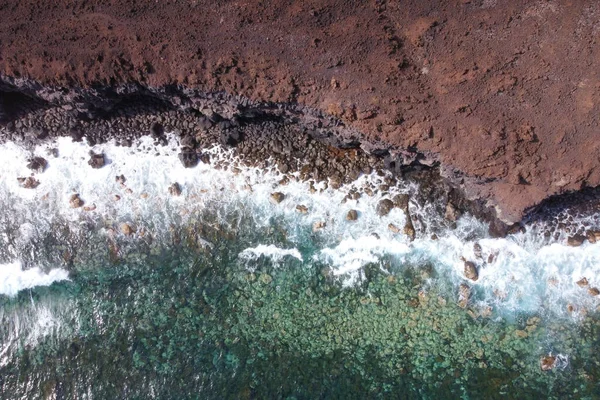 Aerial top view of waves splashing on rocky volcanic coastline. High quality photo. — Stock Photo, Image