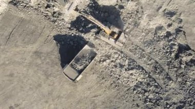 Kazıcı maden kamyonuna mineral yüklüyor. Açık çukur madeni, çıkarıcı endüstri, üst görüş hava aracı.