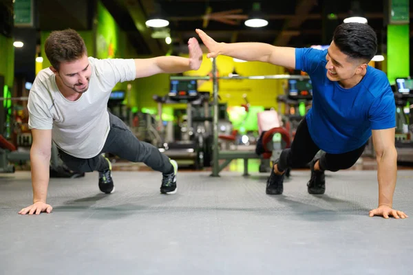 Twee jonge mannen doen hoge planken in de sportschool. — Stockfoto