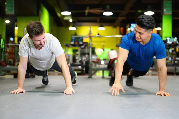Twee jonge mannen doen hoge planken in de sportschool. — Stockfoto