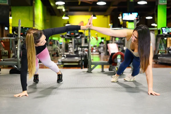 Deux femmes sportives faisant cinq tandis que l'entraînement pousser vers le haut de l'exercice dans le gymnase. — Photo