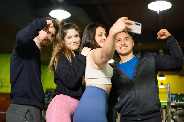 Счастливые друзья со смартфоном делают селфи в спортзале — стоковое фото