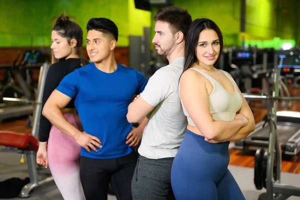Group of young athletic female and male adults standing together as good friends in gym after workout session — Stock Photo, Image