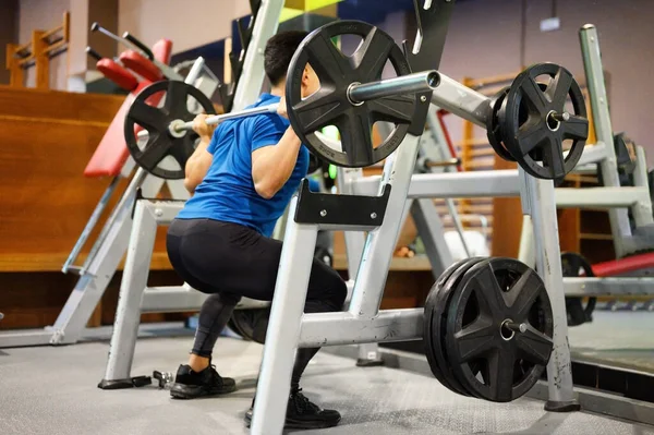 Fit man faire des squats dans une machine d'entraînement. — Photo