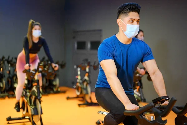 Jeunes Spinning dans la salle de fitness avec masque protecteur pendant l'épidémie de coronavirus. — Photo