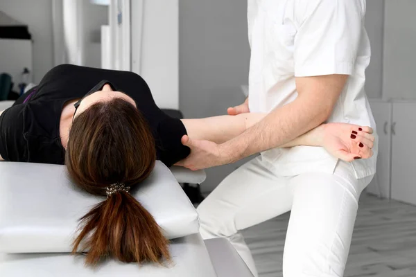 Mannelijke therapeut het geven van massage ter verlichting van schouderpijn aan een vrouwelijke patiënt in fysiotherapie kliniek. — Stockfoto