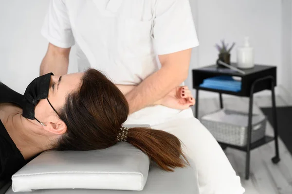 Terapeuta masculina dando masaje para aliviar el dolor de hombro a una paciente femenina en la clínica de fisioterapia. —  Fotos de Stock