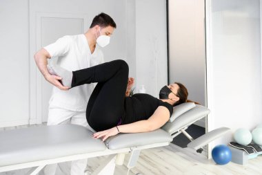 Koruyucu maskeli fizyoterapist hastasına masaj yapıyor. Covid-19 salgınında fizyoterapi güvenlik önlemleriyle tekrar açılıyor. Osteopati, tedavi edici kiromasaj.