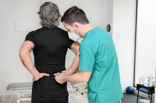 Vista posteriore di un fisioterapista che esamina l'uomo indietro. — Foto Stock