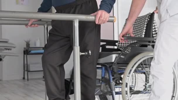 Manlig sjuksköterska som assisterar en äldre handikappad patient i rullstol på rehabiliteringscenter. — Stockvideo