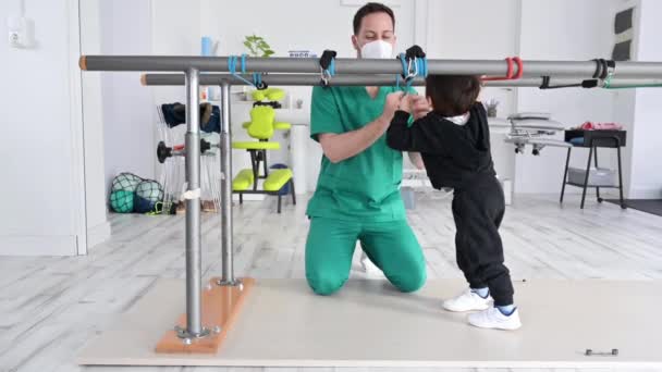 Gyermek agyi bénulással fizioterápián egy gyermekterápiás központban. A fogyatékos fiú fizioterapeutákkal végzett gyakorlatokon vesz részt a rehabilitációs központban.. — Stock videók