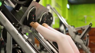 Spor salonunda egzersiz makinesinde kaslarını esneten formda genç bir sporcunun yan görüntüsü..