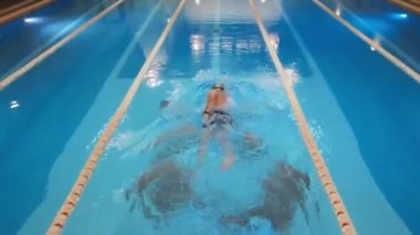 Havadan, İHA 'dan aşağı profesyonel yüzücü görüntüsü, yüzme havuzunda yüzme..