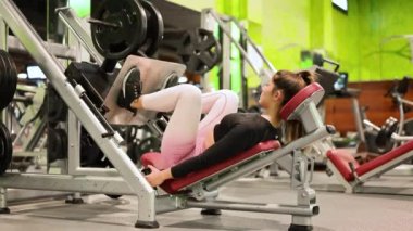 Spor salonunda egzersiz makinesinde kaslarını esneten formda genç bir sporcunun yan görüntüsü..
