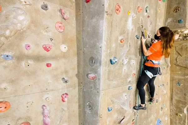 Young fit woman climbing on indoor rock wall.