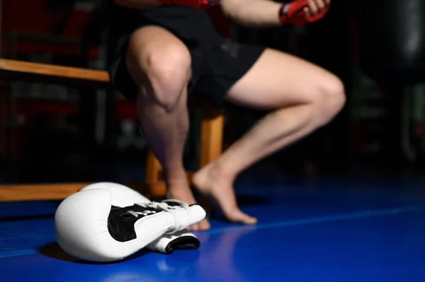 Sluiten van de boxerbenen rustend op de bank in de sportschool na de training. — Stockfoto