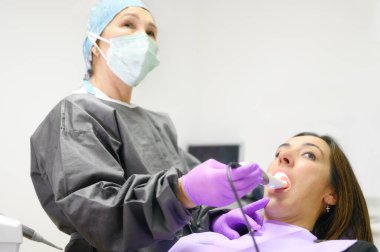 Doktor hastaların dişlerini intraoral kamerayla muayene ediyor.