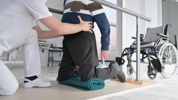 Fyzioterapeut pomáhá invalidnímu vozíku starší muž cvičení v rehabilitační centrum. — Stock video
