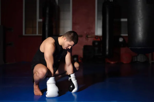 Kickboxing lutador em luvas de boxe de pé sobre os joelhos. — Fotografia de Stock