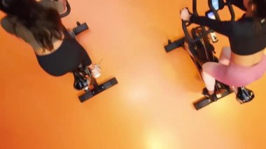 Spor salonunda bisiklete binen insanların hava görüntüsü.