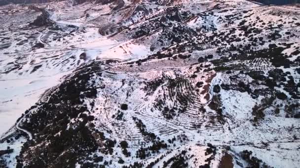 Widok z lotu ptaka na pokryte śniegiem wysokie góry o zachodzie słońca — Wideo stockowe