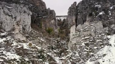 Kış manzarasında dar bir kanyonda ileri doğru uçan bir hava çekimi..