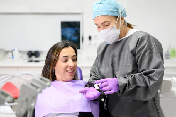 Tandarts toont aan vrouw patiënt een orthodontische siliconen trainer. Mobiel orthodontisch toestel voor tandheelkundige correctie. Rechtenvrije Stockfoto's