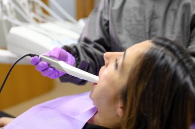 Doktor hastaların dişlerini intraoral kamerayla muayene ediyor.