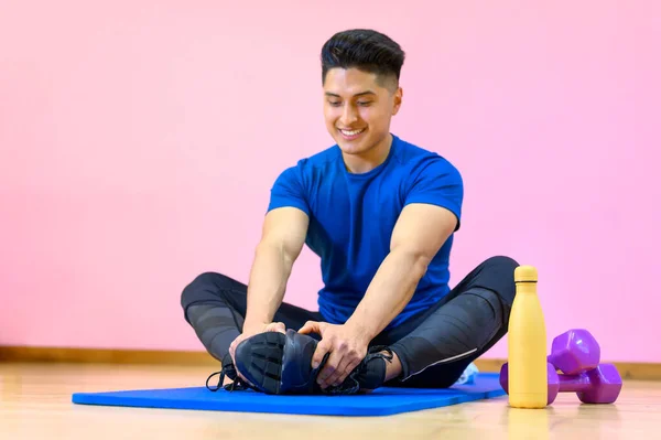 Young Hispanic man practicing yoga on his mat at gym on pink background. — Stock Photo, Image