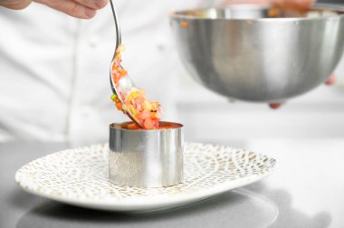 Bir şef lezzetli sebzeleri tartar hazırlar ve hazırlığı biraz klasla tamamlar. Aşçı, mutfak, restoran, yemek kavramı.