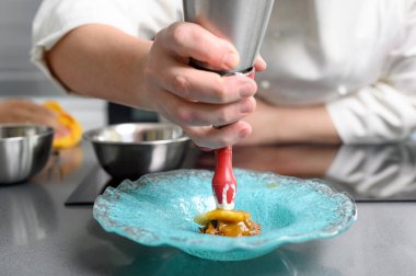 Profesyonel bir aşçı restoranın mutfağında köpük hortumu tutuyor..