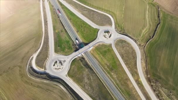 Vista aérea de un avión no tripulado sobre una intersección de carreteras rurales. Tráfico en sobrevuelo en el paisaje rural — Vídeo de stock