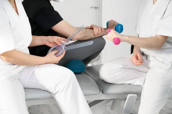 Diverse team van professionals in de gezondheidszorg dragen beschermende gezichtsmasker, werken in een fysieke revalidatie kliniek tijdens coronavirus pandemie. Stockafbeelding