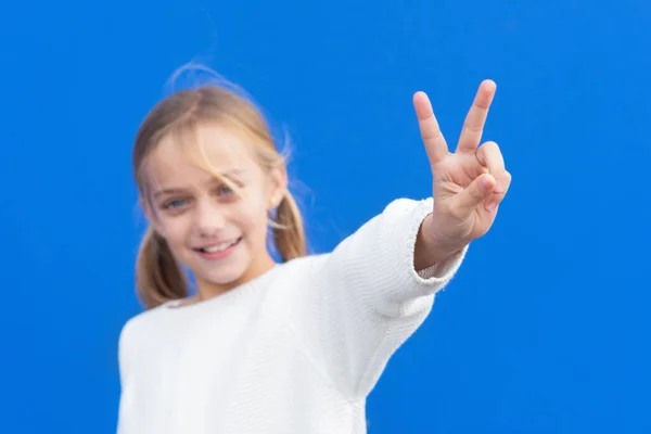 Menina loira bonita nova vestindo camisola casual sobre fundo azul sorrindo olhando para a câmera mostrando os dedos fazendo sinal de vitória. Número dois.. — Fotografia de Stock