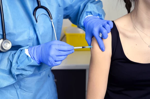 Close-up van jonge vrouw krijgen gevaccineerd, coronavirus concept. Stockfoto