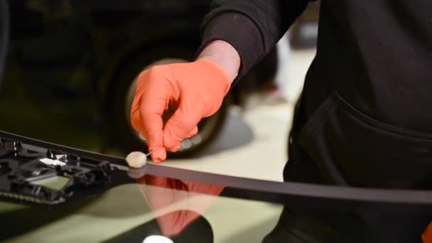 Primer plano del trabajador técnico del automóvil reemplazando el parabrisas de un coche en el garaje de la estación de servicio del automóvil. — Vídeos de Stock