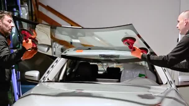 Autó technikus munkás cseréje szélvédő egy autó az autó benzinkút garázsában. — Stock videók