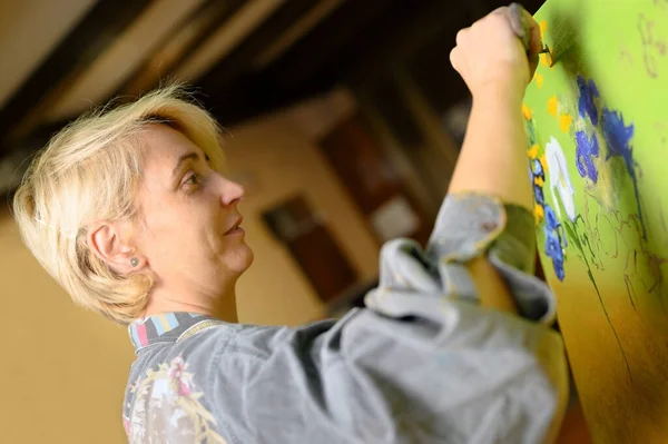 Kobieta artysta artysta malarz skoncentrowany i natchniony obraz malarski z pędzlem i kolorami olejnymi na płótnie. — Zdjęcie stockowe