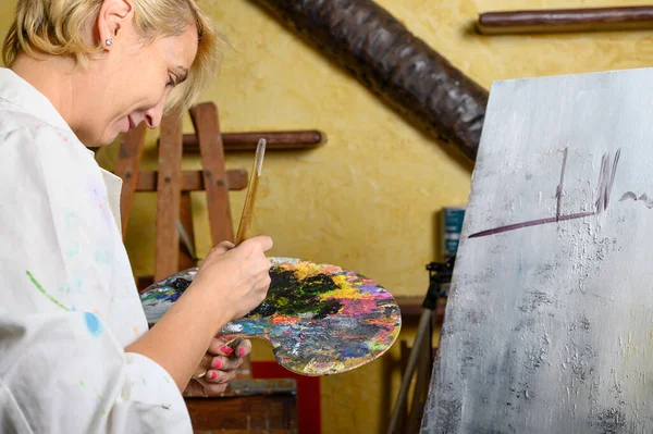 Kreatywna kobieta malarka miesza paletę farb olejnych w palecie. Widok z bliska — Zdjęcie stockowe