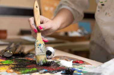 Yaratıcı kadın ressam palette yağlı boya paleti karıştırıyor. Yakın çekim görünümü