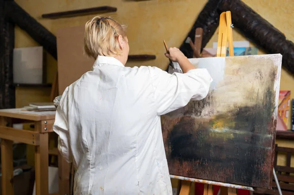 Pittore artista creativo femminile concentrato e ispirato quadro pittura con pennello e colori ad olio su tela. — Foto Stock