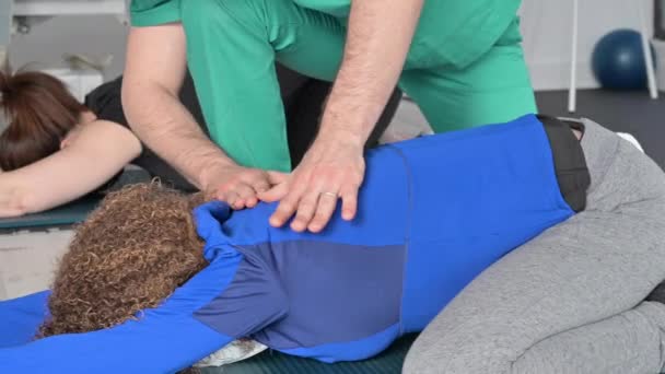 Mujeres estirándose en el suelo con la ayuda de un fisioterapeuta. — Vídeos de Stock