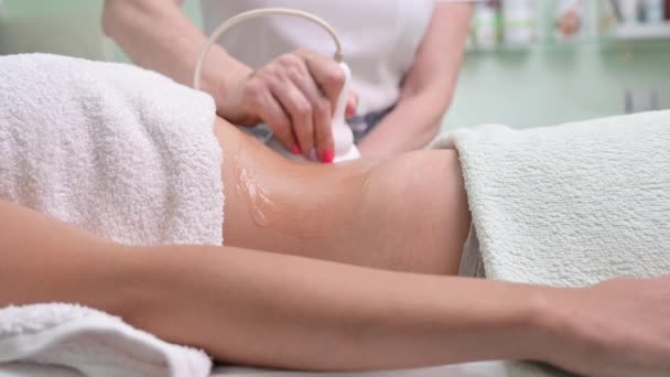 Kobieta poddawana kawitacji ultradźwiękowej przez kosmetologa. klientka korzystająca z zabiegu antycellulitowego w salonie piękności. — Wideo stockowe