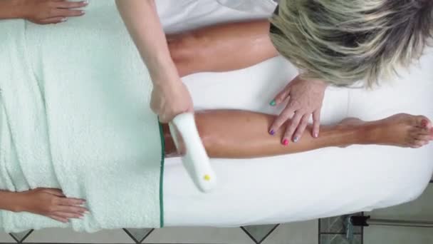Ovanifrån av patienten liggande ner få en laserbehandling för hårborttagning av ben — Stockvideo