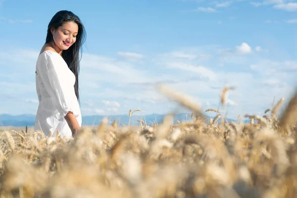 Young Hispanic woman in white dress walking in the middle of a wheat field smiling. — Stock Photo, Image