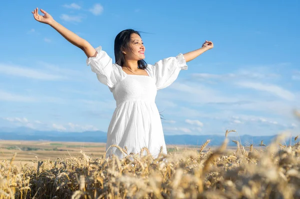 Portret szczęśliwej młodej kobiety w białej sukience, na polu pszenicy. Koncepcja stylu życia i szczęścia. Kobieta z otwartymi ramionami . — Zdjęcie stockowe